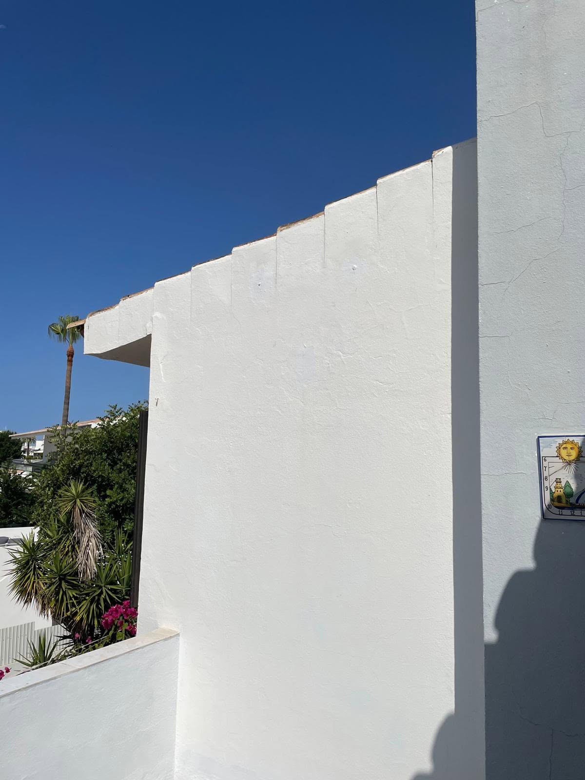 After: the same villa wall with the satellite dish gone, holes filled and the render repainted clean white